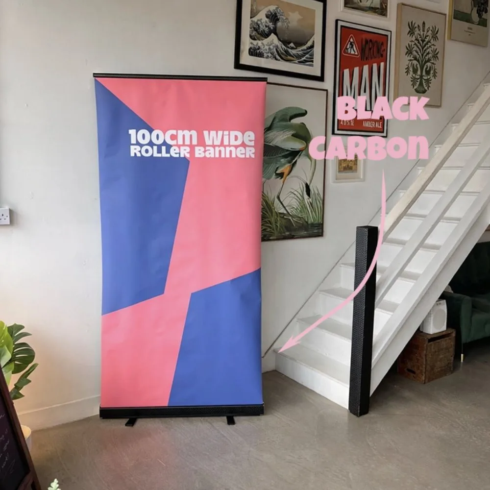 100cm wide pink and blue roller banner standing next to a Black Carbon roller banner stand